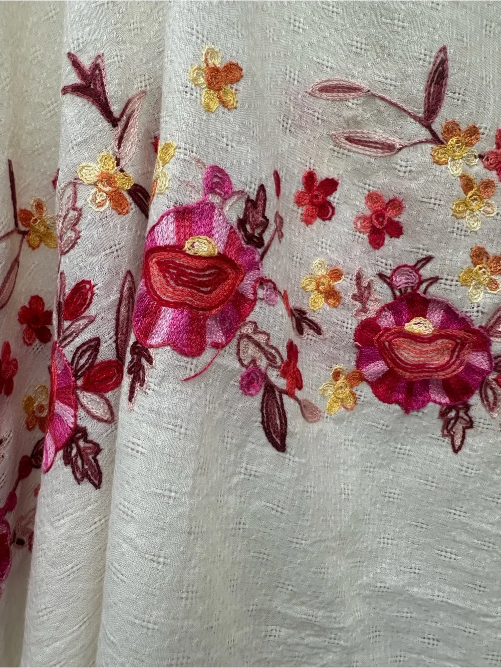 Soft cream cotton-mul feel poncho with vibrant pink, red floral embroidery.